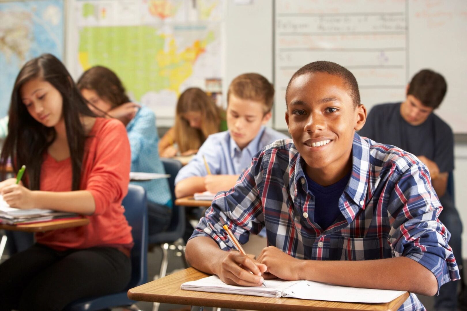 Smiling student writing at school desk